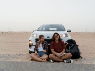 Couple sitting in front of car on road trip
