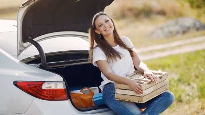 Woman sitting on car boot