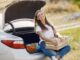 Woman sitting on car boot